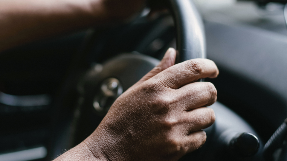 person of colour holding car steering wheel